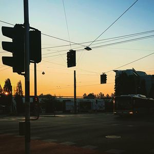 Silhouette city street against sky during sunset