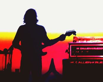 Rear view of silhouette man standing against orange sky