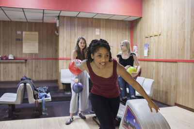 A young woman bowling with friends.