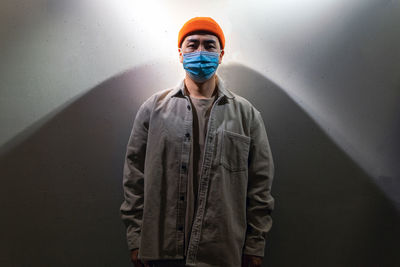 Portrait of young man standing against wall