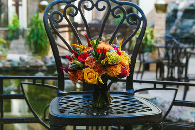 Bouquet of orange roses and alstromeria on a black metal forged chair