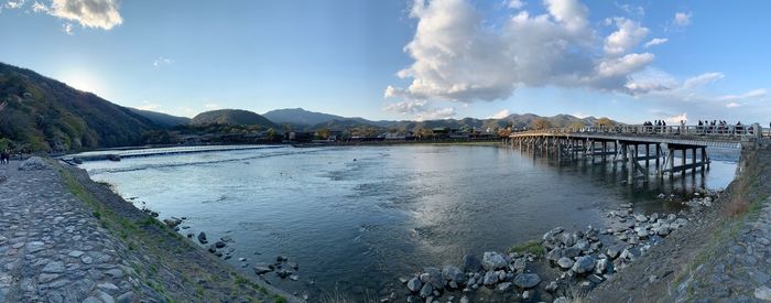 Panoramic view of togetsu-kyo bridge, japan  over river against sky