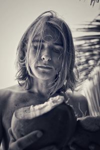 Close-up of shirtless man holding coconut