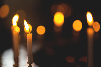 Close-up of lit candles in temple at night