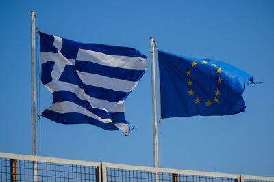 Low angle view of flags against clear blue sky