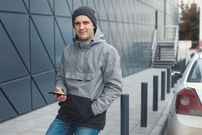 Portrait of man using phone on footpath