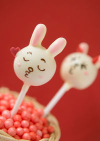 Close-up of cake pops in basket against red background