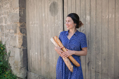 Young woman standing with french baguettes in the countryside