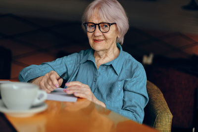 Smiling senior woman wearing eyeglasses sitting at table