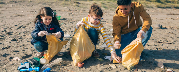 Siblings picking garbage at beach