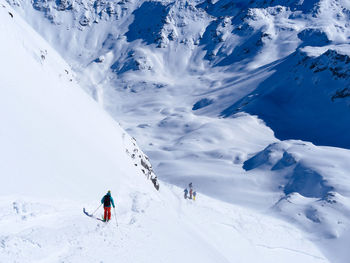 People skiing on snowcapped mountain against sky