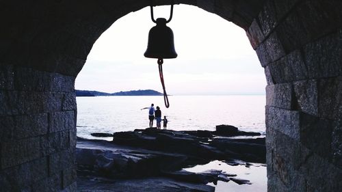 People standing on rock against sea