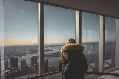 Rear view of woman looking through window