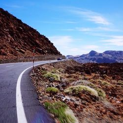 Road leading towards mountains against sky