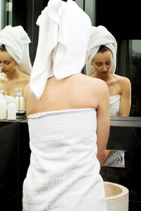 Woman wrapped in towel while standing in bathroom