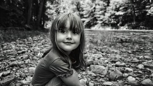 Portrait of smiling girl sitting on stones in forest