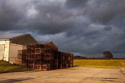 Built structure on field against storm clouds