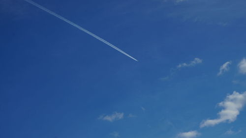 Low angle view of vapor trails in blue sky