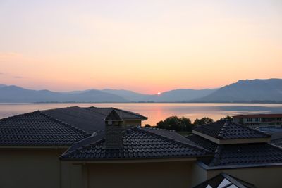 Houses and buildings against sky during sunset