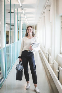 Portrait of smiling young female student in corridor of university