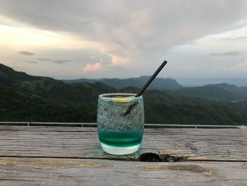 Glass of water on table against mountains