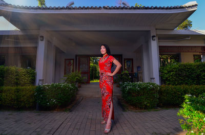 Portrait of woman standing by red building