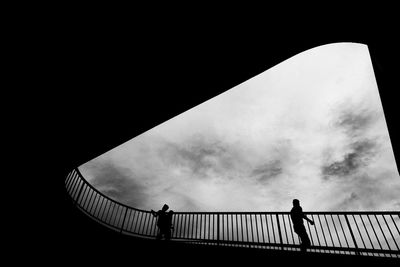 Low angle view of silhouette people on staircase against sky