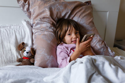 Smiling child laying in the bed under blanket