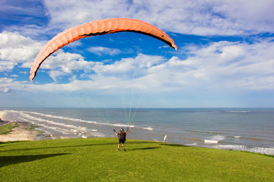Rear view of man paragliding over sea against sky