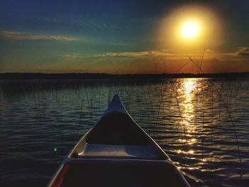 Boat sailing in lake against sky during sunset