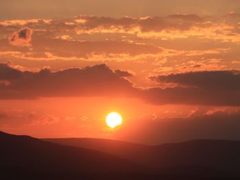 Scenic view of silhouette mountains against orange sky