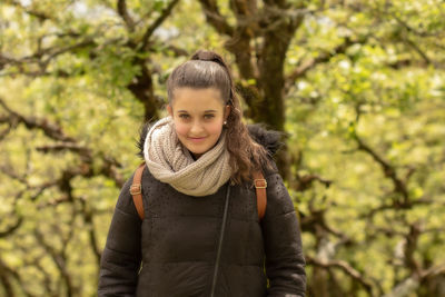 Portrait of young woman standing against trees