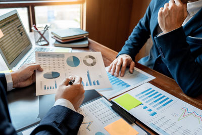 Midsection of business people working on table