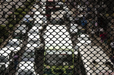 High angle view of vehicles on road seen through chainlink fence