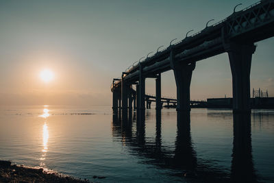 Pier over sea against sky during sunset