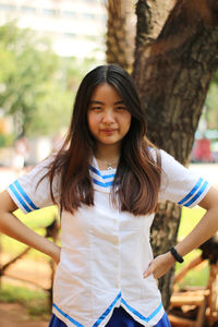 Portrait of sulking young woman with hands on hip standing outdoors