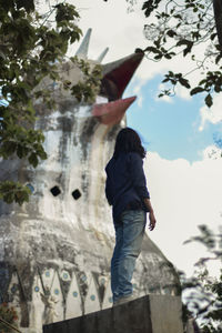 Low angle view of man standing by tree against sky