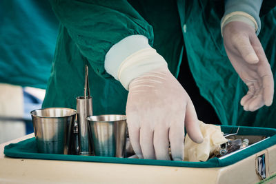 Cropped image of dentist hands picking tool at office