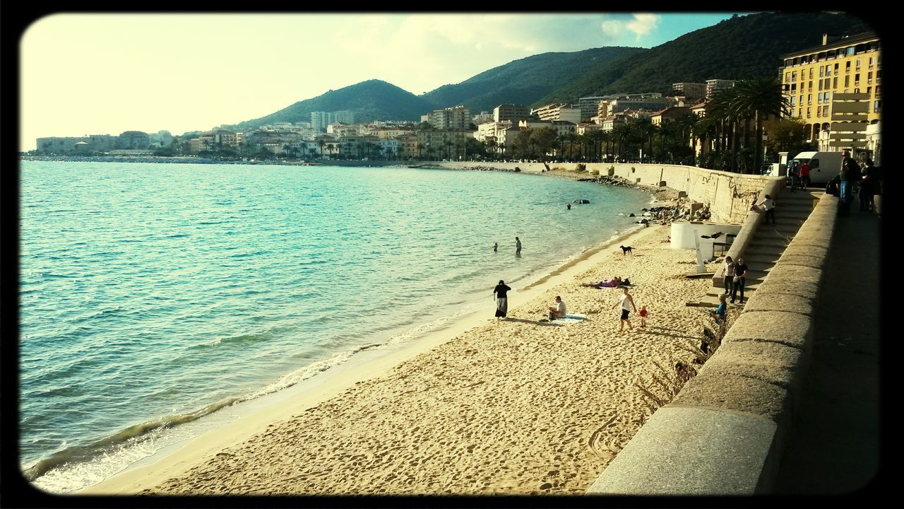 water, building exterior, sea, architecture, beach, built structure, mountain, city, leisure activity, shore, lifestyles, sky, coastline, sand, transfer print, city life, person, men, incidental people