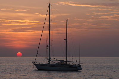 Sailboat sailing on sea against sky during sunset