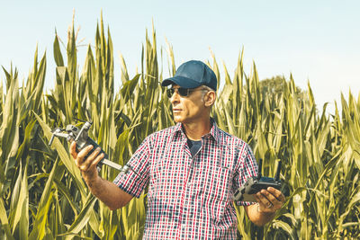 Man holding drone while standing against plants