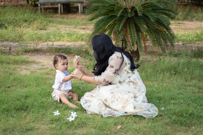 Mother giving flower to cute baby boy and enjoying each other at outdoor