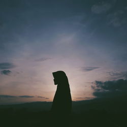 Silhouette woman wearing hijab standing against sky during sunset