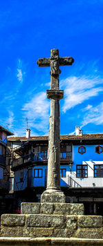 Low angle view of statue by building against sky