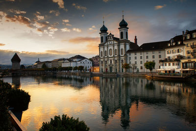 Reflection of buildings in canal against sky at sunset