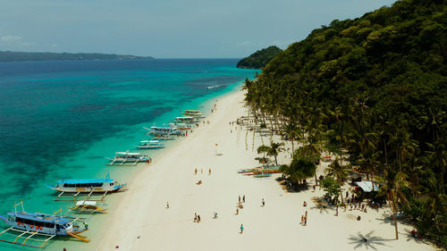 Sand beach with tourists and turquoise water on boracay, philippines, aerial drone. 