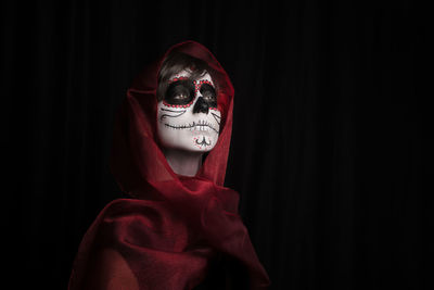 Close-up of young woman with face mask against black background