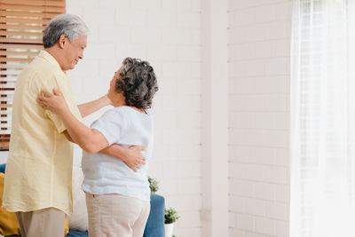 Rear view of couple standing against the wall