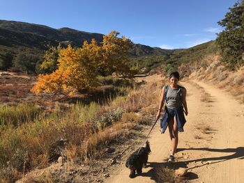 Full length of woman walking with dog on pathway