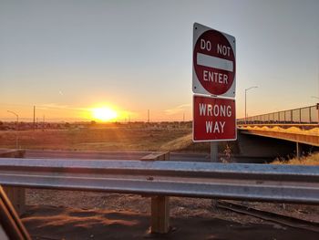 Information sign on road against sky during sunset